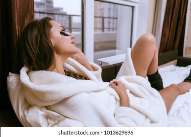 A Cute Young Girl In A White Terry Dressing Gown Lies In Bed, Under The Eyes Of Black Patches