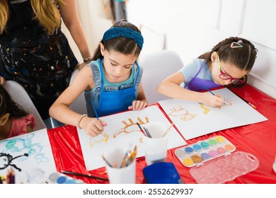 Cute young girls painting animal figures with watercolors during their elementary school art class - Powered by Shutterstock