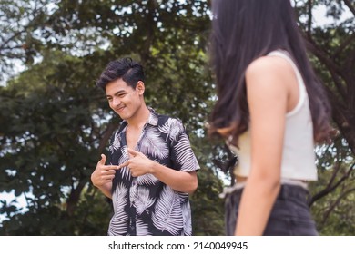 A cute young guy being shy while conversing with a girl. Interested to know the person but feeling anxious. Keeping his distance.
