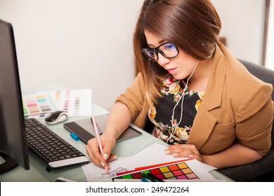 Cute young Hispanic designer working on some sketches while listening to music - Powered by Shutterstock