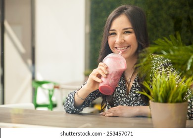 Cute Young Hispanic Woman Taking A Smoothie Break At A Juice Bar