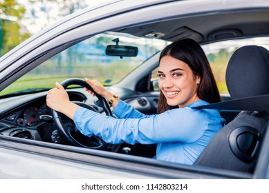 Cute Young Lady Happy Driving Car. Image Of Beautiful Young Woman Driving A Car And Smiling. Portrait Of Happy Female Driver Steering Car With Safety Belt
