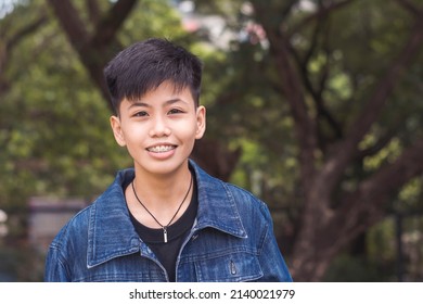 A cute young lesbian woman in happy thoughts. Delighted about the compliments about her. Standing outside the park. - Shutterstock ID 2140021979