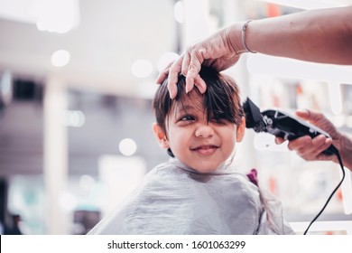 Cute young little boy getting a haircut at salon