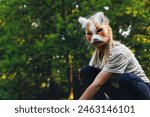 Cute young little kid girl wear cat furry mask enjoy have fun playing outdoors in forest street park. Children therian wild animal character trendy fan culture. Teenager social expression hobby