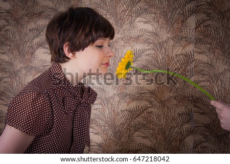 Cute, young model with short hair poses with vintage styling. Patterned wallpaper, 1960's or 1970's concept. Polyester fashion of seventies.