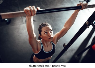 Cute young muscular girl doing pull-ups exercise at the gym.  - Powered by Shutterstock