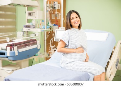 Cute Young Pregnant Brunette Sitting In A Hospital Bed And Waiting For Her Obgyn