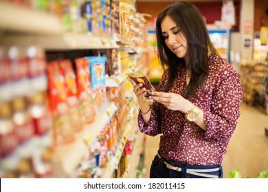 Cute Young Woman Examining A Product Label While Shopping At The Store