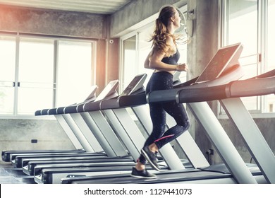 Cute Young Woman Exercising On  Treadmill At A Gym.Active Young Woman Running On Treadmill. Smile And Funny Emotion.