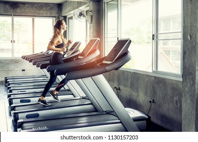 Cute Young Woman Exercising On  Treadmill At A Gym.Active Young Woman Running On Treadmill. Smile And Funny Emotion.