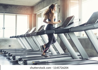 Cute Young Woman Exercising On  Treadmill At A Gym.Active Young Woman Running On Treadmill. Smile And Funny Emotion.