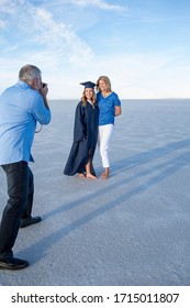 Cute Young Woman In Her Graduation Cap And Gown Taking A Picture With Her Mom. Beautiful Girl Smiling And Hugging Her Parent After Finishing Her Degree. Celebrating This Big Milestone