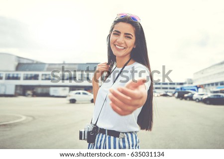 Cute young woman holding out her hand in a gesture of invitation as she stands smiling at the camera in town Stock photo © 