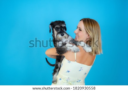 Cute young woman hugs her puppy schnauzer dog. Love between owner and dog. Isolated on white background. Studio portrait.
