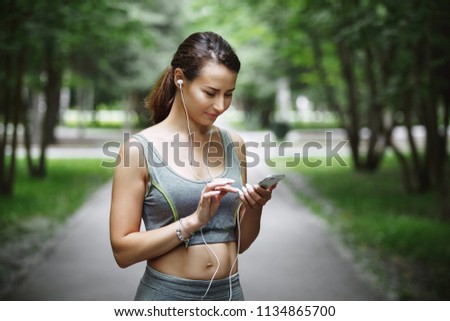 Similar – Woman with earphones listening music in smartphone