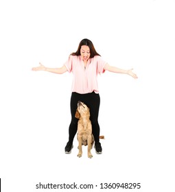 Cute Young Woman Looking Down At A Golden Retriever Puppy Dog Sitting Down Between Her Legs Against A White Background