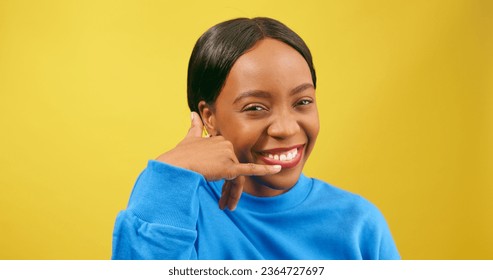 Cute young woman makes Call Me symbol with hand, flirting, yellow studio - Shutterstock ID 2364727697