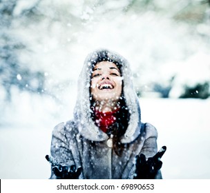 Cute young woman playing with snow in fur coat outdoors Foto Stok