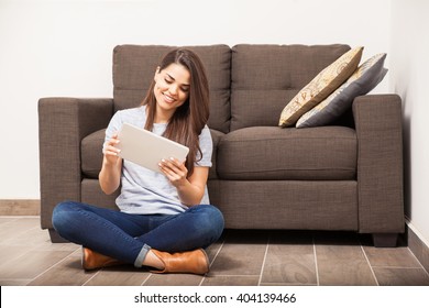 Cute Young Woman Relaxing At Home And Watching A Tv Show On A Tablet Computer