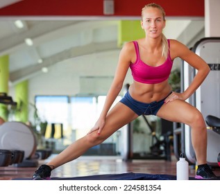 Cute young woman stretching and warming up before working out at a gym - Shutterstock ID 224581354