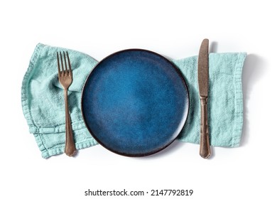 Cutlery With A Blue Plate. A Fork, A Knife, And A Dish On A Teal Napkin, Overhead Flat Lay Shot On A White Background