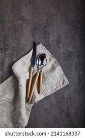 Cutlery on a light linen napk on rust old heavily worn black navy blue concrete texture or background. With place for text and image