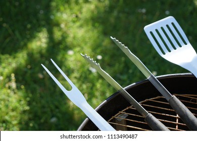 Cutlery for sausages barbecue with a charcoal barbecue in the garden