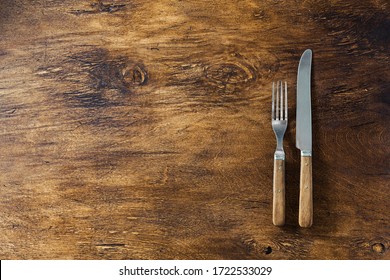 Cutlery with wooden handles on a wooden surface, top view. - Powered by Shutterstock