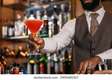 Cutout of a black bartender offering a cocktail served in a martini glass in a traditional cocktail bar - Powered by Shutterstock