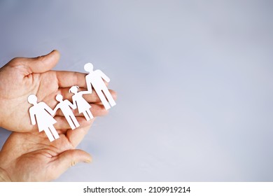 Cutout paper chain family with the protection of cupped hands, concept for security and care. Hands with cut out paper silhouette on table. Family care concept - Powered by Shutterstock