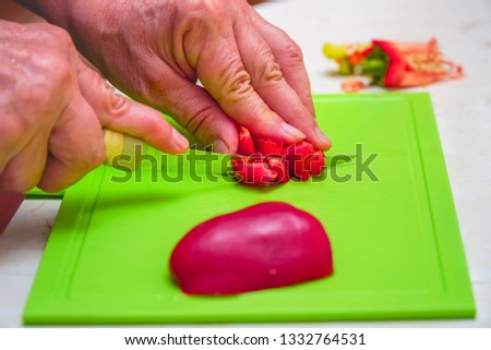 Cuts with a knife into pieces and slices red bell pepper