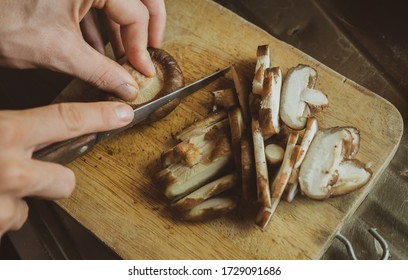 Сook cuts shiitake mushrooms at home kitchen table - Powered by Shutterstock