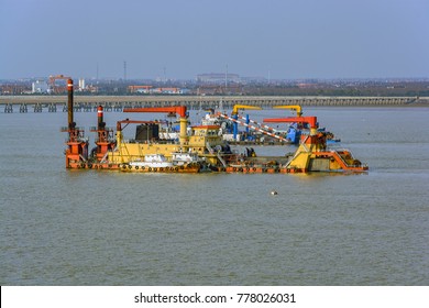 Cutter Suction Dredger At Work Of Land Reclamation For New Ports Positioned On Spuds As Anchors And Discharge Dredged Soil Through A Floating Pipeline. Shanghai, China