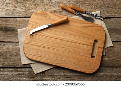 Cutting board, cheese knives and fork on old wooden table, flat lay - Powered by Shutterstock