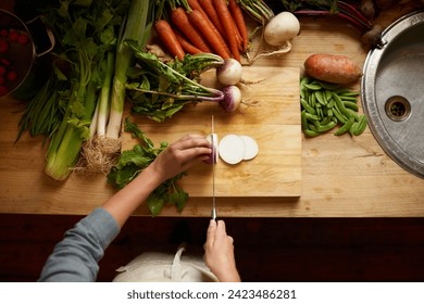 Cutting, board and hands with vegetables for healthy food, cooking or preperation of soup ingredients on table. Chef or person above in kitchen with organic groceries and potato for a vegan dinner