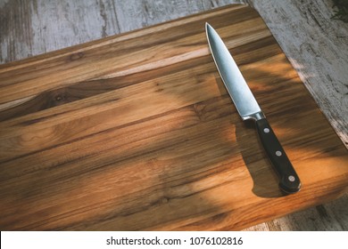 Cutting board and a kitchen knife on old wooden background selected focus