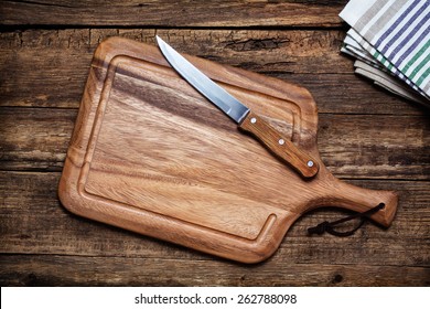 Cutting Board And A Kitchen Knife On Old Wooden Background. Top View 