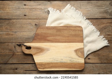 Cutting board and kitchen towel on wooden table, flat lay. Cooking utensil