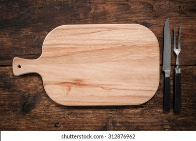 Cutting board, knife and fork on a rustic background  - Powered by Shutterstock