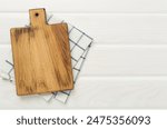 Cutting board with napkin on wooden background, top view