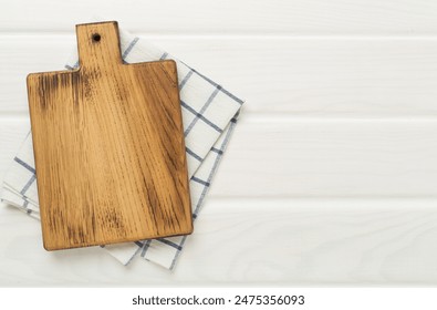 Cutting board with napkin on wooden background, top view