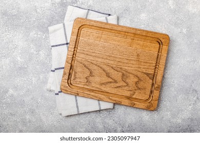 Cutting board over kitchen towel on gray kitchen table texture background. Recipe. Kitchenware. Empty modern wooden cutting board. Menu. MOCKUP. Place for text. Place to copy. - Powered by Shutterstock