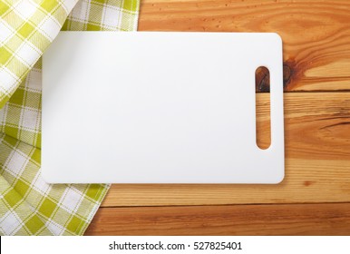 Cutting Board Over Towel On Wooden Kitchen Table. Top View