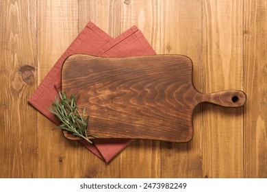 Cutting board, rosemary and napkin on wooden table, top view. Space for text - Powered by Shutterstock