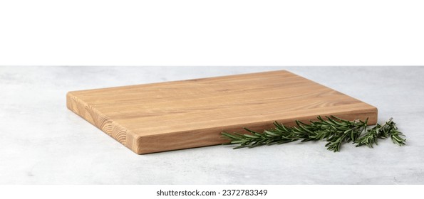 Cutting board and rosemary on a grey stone table. Isolated on a white background. Culinary background. Empty wooden cutting board, product display space. - Powered by Shutterstock