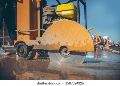 cutting concrete floor with worker cutting concrete road with diamond saw blade machine