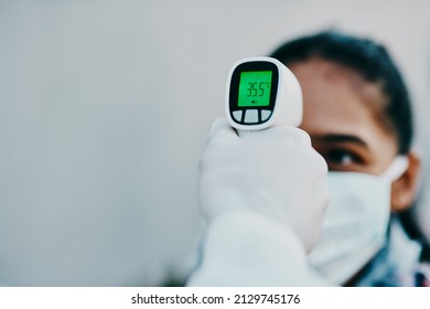 Cutting Edge Tech To Help Curb The Spread. Shot Of A Young Woman Getting Her Temperature Taken With An Infrared Thermometer By A Healthcare Worker During An Outbreak.