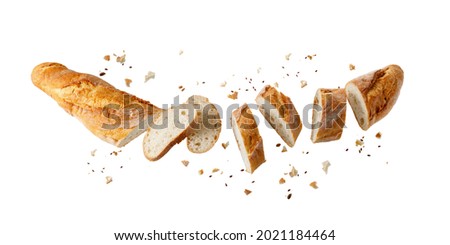 Cutting fresh baked loaf wheat baguette bread  with crumbs and seeds flying isolated on white background. 