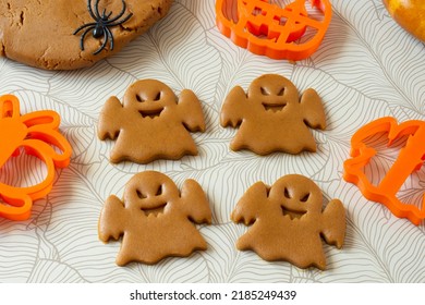 Cutting Halloween gingerbread in shape of ghosts from dark honey dough with spices. Dough, rolling pin and Halloween cookie cutter on table - Powered by Shutterstock